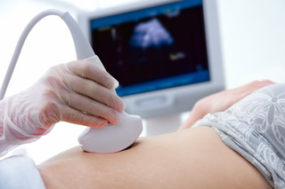 a wand being moved on a woman's belly for an ultrasound being done after an ultrasound order